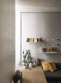 Neon lights are fitted within a series of perforations in the white laminate to break up the rigid geometry of the space.