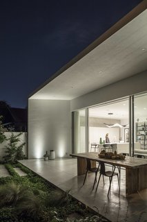 At the back of the house, a glazed wall slides open to connect with a spacious green terrace.