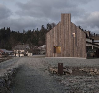 The gable silhouette of the house harmonizes with its rural setting.