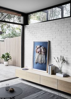 Washed oak joinery and textured tiles add warmth to the space, providing a soft contrast to the crisp concrete and brick. 