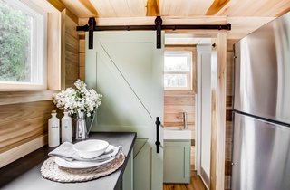 Behind a sliding barn-style door is a bathroom with a shower and toilet. 