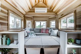 The living room is designed as an elevated U-shaped sitting lounge. This space is surrounded by windows that draw in plenty of natural light.