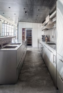 A sloped wall of framed windows serve as cues to visually guide one from the kitchen and dining area into the master bedroom.