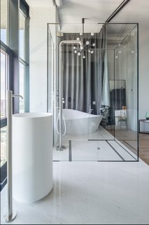 A glass wall separates the ensuite bathroom from the bedroom, allowing additional natural light to flood the space. A curtain can be drawn along this wall when privacy is needed.