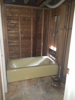 The old bathroom had Formica wood paneling and a yellow tub. 