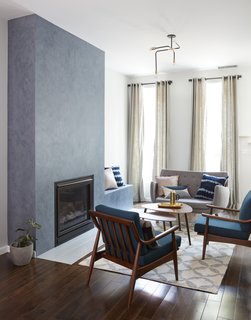 The original layout had a tiny living area in the front that wasn’t spacious enough to accommodate entertaining. To create more space, Tang converted the second floor into a larger living room. Here, chairs and sofa from All Modern; drapery and rug from West Elm; fireplace custom-finished in Venetian plaster; light fixture from Lambert et Fils. 