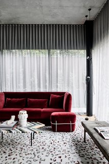 A lavish, velvet-upholstered red sofa in the living room.