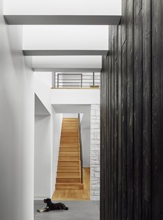 From the double-height entry hall, a staircase leads to the living area on the new upper level. 