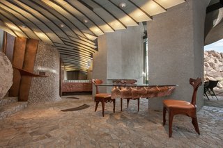 Glass-topped tables with carved marble or wood bases, some cantilevered from concrete columns, look like the spines or rib cages of prehistoric creatures. 