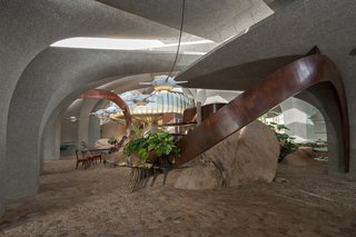 To harmonize the interiors with the otherworldly character of the house, Vugrin built tables and shelves that swept across rooms from the ceiling to the floor. 