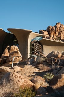 The lower solid, concrete portion brings to mind elements of Native American adobe pueblos, while the sculptural form of the upper section conjures images of dinosaur fossils or spaceships.