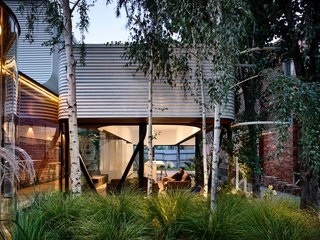 The glass pavilion that sits in the middle of the existing garden offers a wonderful contrast to the dark masonry walls and the sturdy, two-story terraces on its flanks.