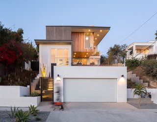 A separate two-car garage is located near the entrance of the house, which has a bike rack and planters out front.