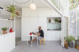 A pull-out dining table is concealed behind one of the white kitchen panels.