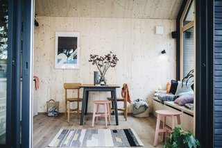 A four-person dining table is sited near the large picture window on the wider end of the house.
