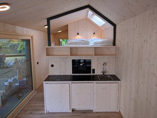 The kitchenette includes a fridge, laundry machine, an integrated coffee machine, and a regular-size cooktop.