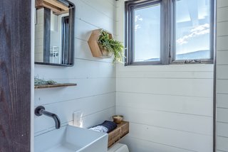 The bathroom includes a Separett Villa compost toilet, a shower, and vanity. A black hexagonal tile with white grout was used for the bathroom floor. 
