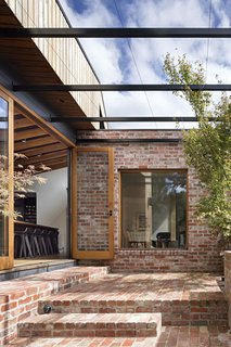 A steel pergola creates an outdoor living space; in the summer, grape vines climb up to create a lush canopy.