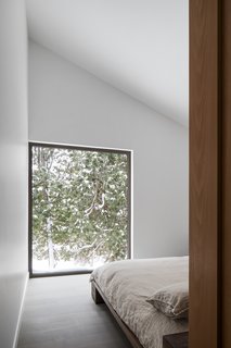 Set back from the main living areas, the master bedroom provides peaceful views of the cedars outside.