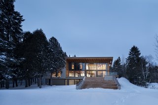 The house has an exposed wooden structure and a large terrace with wide steps set over the basement of the original house.