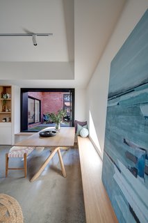 A built-in bench wraps around a corner as seats for the dining table. The artwork is by watercolorist Stefan Gevers.