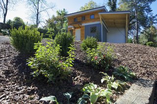The tiny home's exterior features eastern cedar siding, painted Hardie Board, corrugated metal accents, casement windows, and a charcoal grey standing seam metal roof.