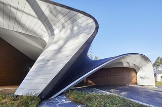 The roof's siding is made of painted plywood, and the facade is constructed from glass and spruce logs.