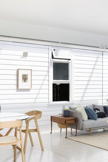 A new living lounge and dining area in the extension are awash in light. External cladding continues inside, uniting old and new spaces.