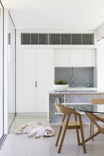 An open-plan kitchen and dining area within the addition feature white cabinets.