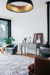 The living room is a comfortable, serene space with a balance of prints and textures presided over by a bold Galileo pendant from Lights Lights Lights.