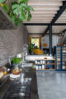 The simple, efficient kitchen features a stainless-steel counter. From the kitchen, another staircase descends to a basement with a utility room, larder, and TV area.