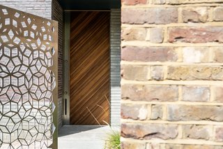 Metal, brick, and wood harmonize near the entrance of the house.