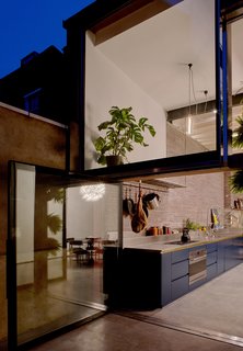 Large, pivoting glass doors connect the kitchen with a patio.