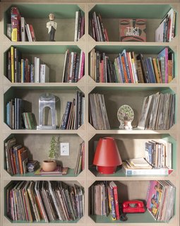 "The shelves with green-painted interiors—a nod to the cases found in old bookshelves—house the artist’s collection of comics, vinyl records, and objects," says Semerene.