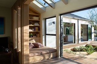 A dramatic vaulted foyer leads to a formal sitting room flanked by two custom seating areas with built-in day beds and louvered sun screens. The sun-lit space makes for an ideal reading nook.