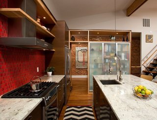 This Washington DC row house conversion maintains an industrial feel courtesy of brick walls, dark woods, and a fiery red backsplash wall.
