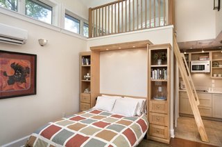 Built-ins, such as this Murphy Bed wall of storage, accommodate living in a small footprint. The ladder accesses a small loft above the bathroom for additional living space.