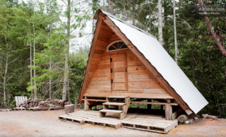 This small, rustic, hand-built cabin deep in the Northern California woods is part of a remote, off-grid "village" that includes a few other cabins, goats, chickens, dogs, cats, permaculture gardens, and all kinds of cool, sustainable, DIY infrastructure. 