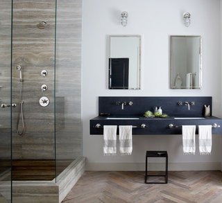 Subtler shading works here for New York City–based designer Jenny Wolf, who used mirrors and patterns for this windowless bathroom. Tall mirrored medicine cabinets and a glass shower amplify light from the interior fixtures, brightening up the space. Wolf used built-in cabinets to save floor space. A herringbone wood floor gives the illusion of a larger and warmer bath.