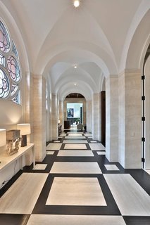 With no interior partitions dividing up the space, one of the long side aisles of this converted 1910 brick church in Toronto, Canada, maintains the rhythm of the groin vaults, now plastered over and lit with minimalist fixtures. Light and the decorative windows (whose stained glass was removed), can be seen from opposite ends of the home.