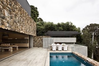 These 4 Modern Homes Around the World Take Advantage of Local Stone - Photo 3 of 16 - Stone walls surround the patio area and the edge of the pool.