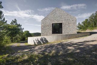 These 4 Modern Homes Around the World Take Advantage of Local Stone - Photo 7 of 16 - One of the three large windows in the home is positioned on the end gable that looks out onto the landscape.