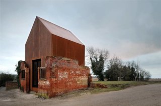 The dilapidated brick structure and the smooth Cor-Ten steel create a balance between old and new.