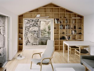 The interiors frame selective views of the existing rock walls, and contrast them with light finishes of white walls and wood furniture and shelving.