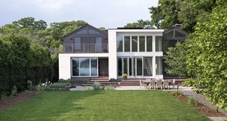 At this riverside home designed by Sellars Lathrop Architects, the gabled roofs of the original 1950s structure were maintained. They provided a foil on which to create a stark contrast between old and new. The addition is distinct in both its white facade with rectangular windows and its flat rather than angled roofs.
