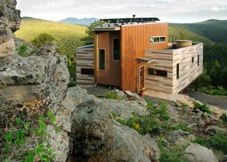 Within the 1500 square feet of this residence, the Denver, Colorado-based architecture firm Tomecek Studio implemented environmentally sensitive strategies including recycled materials, green roofs, and photovoltaics. The residence is anchored by an existing rock outcropping and takes full advantage of the distant ridge views to the south. The main floor includes two shipping containers that saddlebag a wedge-shaped space. The containers hold the function of bedrooms, bath, office, laundry, and kitchen, while the center space is used for entry, dining, and living. The upper floor is an open loft with a platform bed that slides on tracks outdoors as a reference to the quintessential camping experience.