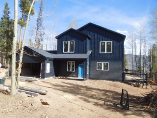This mountain cabin by Liscott Custom Homes was designed as a three-bedroom, three-bath custom home for a family in Silverthorne, Colorado. Measuring 2,400 square feet, the home is clad in contrasting horizontal and board and batten siding coated in a dark, blue-gray finish.