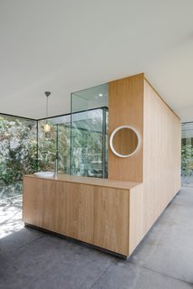 A Portuguese Glass House Uses Surrounding Foliage as a Privacy Screen - Photo 7 of 15 - Bookmatched wood veneer cabinetry brings a warm, tactile feel to the interiors.