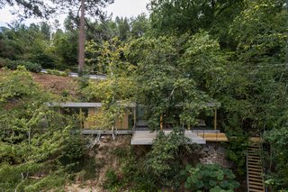 A Portuguese Glass House Uses Surrounding Foliage as a Privacy Screen - Photo 2 of 15 - A large porch projects from the main building.