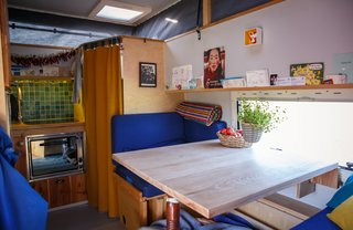 The interior features a compact layout with a wall oven, cooktop, bench seating, and bathroom.